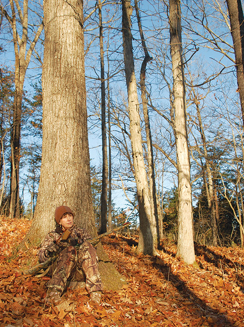 hunting turkey in a fall woods, leaning against a large tree calling turkey